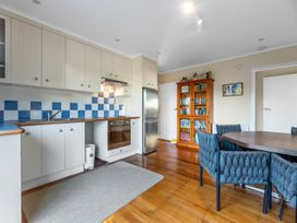A kitchen with a dining table and bookshelf at Beach Galore - Waihi Beach