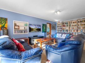 A living room with a sofa and bookshelves at Beach Galore - Waihi Beach
