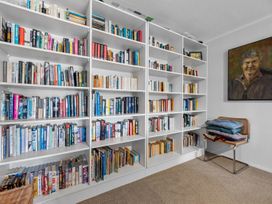 A reading room with bookshelves and a chair at Beach Galore - Waihi Beach