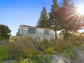 A house with a balcony and trees at Beach Galore - Waihi Beach Holiday Home, Waihi Beach