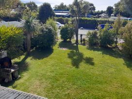 A garden with grass and trees at Kea View - Pohara Beach Holiday Home, Pohara Beach
