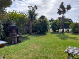 A garden with a grill and palm trees at Kea View - Pohara Beach Holiday Home Pohara Beach