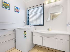 A laundry room with washing machine and sink at The Sandcastle - Papamoa Holiday Apartment in Papamoa