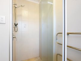 A shower area with tiles and a glass door at The Sandcastle - Papamoa Holiday Apartment, Papamoa