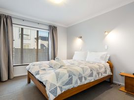 A bedroom with a bed and window at The Sandcastle - Papamoa Holiday Apartment