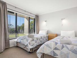 A bedroom with two beds and a dressing table at The Sandcastle - Papamoa Holiday Apartment Papamoa