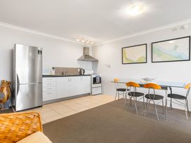 A kitchen with appliances and dining table at The Sandcastle - Papamoa Holiday Apartment Papamoa