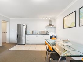 A kitchen with appliances and a dining area at The Sandcastle - Papamoa Holiday Apartment