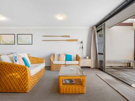 A living room with wicker furniture and artwork at The Sandcastle - Papamoa Holiday Apartment, Papamoa