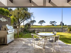 An outdoor area with a barbecue grill and a table with chairs at The Sandcastle - Papamoa Holiday Apartment, Papamoa