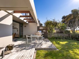 A deck with a table and chairs at The Sandcastle - Papamoa Holiday Apartment