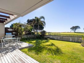 A garden area with table and chairs next to a barbecue at The Sandcastle - Papamoa Holiday Apartment in Papamoa