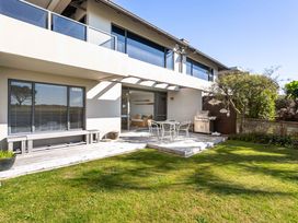 A patio area with a table and chairs at The Sandcastle - Papamoa Holiday Apartment, Papamoa