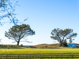 A landscape featuring trees and a blue building in a field at The Sandcastle - Papamoa Holiday Apartment, Papamoa