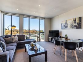 A living room with a sectional sofa coffee table dining table and chairs by large windows at 24 Marina View Retreat Taupo Holiday Apartment Taupo Bay