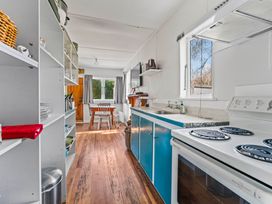 A kitchen with a stove, sink, and dining table at Kingfisher - Kuratau Holiday Home, Kuratau