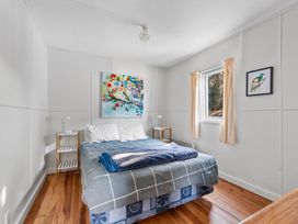 A bedroom with a bed, nightstand, and painting at Kingfisher - Kuratau Holiday Home, Kuratau