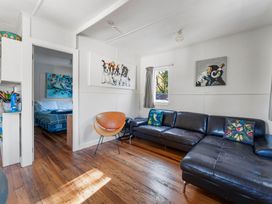 A living room with a sofa, chair, and artwork at Kingfisher - Kuratau Holiday Home, Kuratau