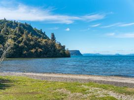A beach with water and mountains at Kingfisher - Kuratau Holiday Home Kuratau