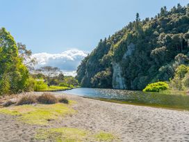 A river and sandy area with cliffs and trees at Kingfisher - Kuratau Holiday Home Kuratau