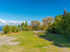 A path alongside grass and trees near a lake at Kingfisher - Kuratau Holiday Home Kuratau