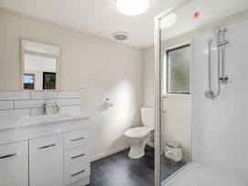A bathroom with a white vanity and sink a toilet a glass-enclosed shower with showerheads and a window at Acacia Views - Acacia Bay Holiday Home in Acacia Bay