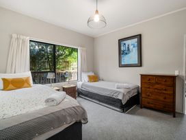 A bedroom with two beds a wooden dresser and a window showing trees at Acacia Views - Acacia Bay Holiday Home in Acacia Bay