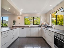 A kitchen with white cabinets black countertop and large windows overlooking greenery at Acacia Views - Acacia Bay Holiday Home in Acacia Bay