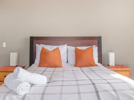 A bed with orange pillows and white rolled towels on a plaid bedspread in a bedroom at Acacia Views - Acacia Bay Holiday Home in Acacia Bay