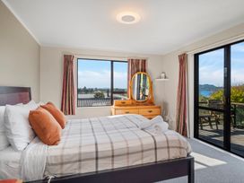 A bedroom with a bed pillows dresser mirror and sliding glass door at Acacia Views - Acacia Bay Holiday Home in Acacia Bay