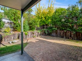 A backyard with a covered patio and paved area surrounded by trees and wooden fencing at Acacia Views - Acacia Bay Holiday Home in Acacia Bay