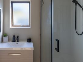 A bathroom with a shower and vanity at Ronas - Whiritoa Beach Bach Whiritoa Beach
