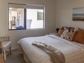 A bedroom with a bed and window at Ronas - Whiritoa Beach Bach Whiritoa Beach