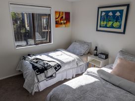 A bedroom with two beds and a nightstand at Ronas - Whiritoa Beach Bach in Whiritoa Beach