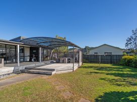 An outdoor seating area with a deck and grill at Fun at Whangamata - Whangamata
