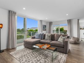 A living room featuring a sofa, coffee table, and large windows at Ruakaka Sands - Ruakaka