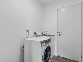 A laundry room with a washing machine and sink at Ruakaka Sands - Ruakaka