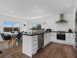 A kitchen with a sink, stove, and dining table at Ruakaka Sands - Ruakaka