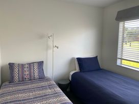 A bedroom with two beds and a lamp at Ruakaka Sands - Ruakaka