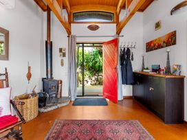 An entryway with a wood stove and a red front door at Treetop Hideaway - Taupo Holiday Home, Taupo Central