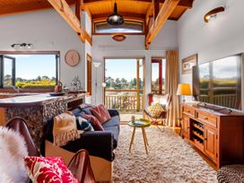 A living room with a sofa, coffee table, and television at Treetop Hideaway - Taupo Central