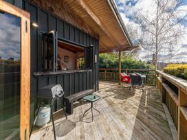 A deck area with a grill and seating at Treetop Hideaway - Taupo Holiday Home Taupo Central
