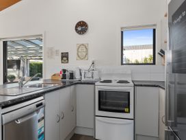 A kitchen with a sink, stove, and coffee maker at Sunnyside Spa Retreat - Mangawhai Heads