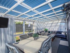 A conservatory with a table and chairs at Sunnyside Spa Retreat - Mangawhai Holiday Home Mangawhai Heads