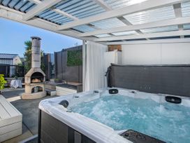 An outdoor space with a hot tub and fireplace at Sunnyside Spa Retreat - Mangawhai Heads