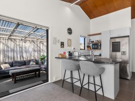 A kitchen with bar stools and appliances at Sunnyside Spa Retreat - Mangawhai Heads