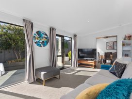 A living room with a sofa and TV at Sunnyside Spa Retreat - Mangawhai Heads