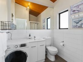 A bathroom with a washing machine and sink at Sunnyside Spa Retreat - Mangawhai Heads