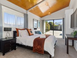 A bedroom with a bed and a nightstand at Sunnyside Spa Retreat - Mangawhai Heads
