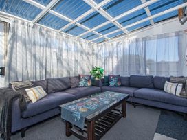 A conservatory with a sofa and table at Sunnyside Spa Retreat - Mangawhai Heads